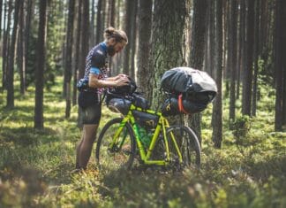 Historie z sakwami: pracę w korpo zamienił na życie w siodełku Rowerzysta bikepackingowy sprawdza sakwy w zielonym polskim lesie