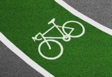 Nowe inicjatywy samorządów: miejskie programy i budżety na infrastrukturę rowerową Jasnozielona ścieżka rowerowa z białym symbolem roweru