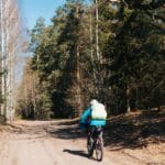 Kolarz jedzie szosą przez wiosenny las podczas samotnej wyprawy