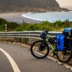 Rowerzysta na nadmorskiej szosie z widokiem na plażę i znakami kierunkowymi