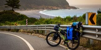 Weekendowy wypad z sakwami: jak wybrać idealną trasę bikepackingową Rowerzysta na nadmorskiej szosie z widokiem na plażę i znakami kierunkowymi