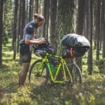 Rowerzysta sprawdza sakwy bikepackingowe w zielonym polskim lesie