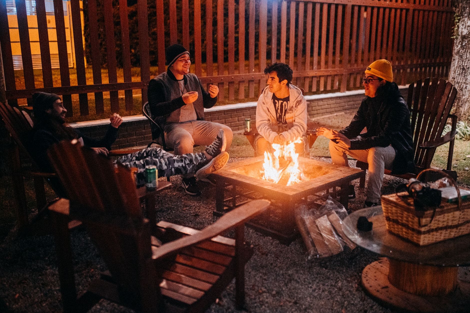 Dwóch podróżników rozmawia przy ognisku, siedząc w fotelach o zmierzchu