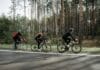 Czy stalowa rama naprawdę jest wygodniejsza na długich trasach Grupa kolarzy jedzie szosą w słońcu, w tle zielony las