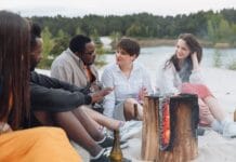 Spotkani przy ognisku: niezwykłe przyjaźnie zrodzone na rowerze Przyjaciele rowerzyści siedzą przy ognisku na piaszczystej plaży
