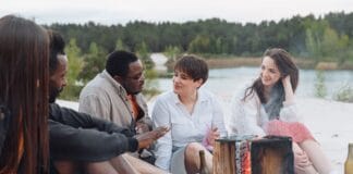 Przyjaciele rowerzyści siedzą przy ognisku na piaszczystej plaży