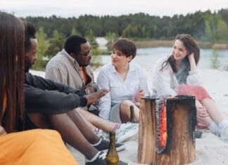 Spotkani przy ognisku: niezwykłe przyjaźnie zrodzone na rowerze Przyjaciele rowerzyści siedzą przy ognisku na piaszczystej plaży