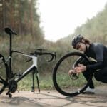 Rowerzysta naprawiający koło roweru na leśnej ścieżce