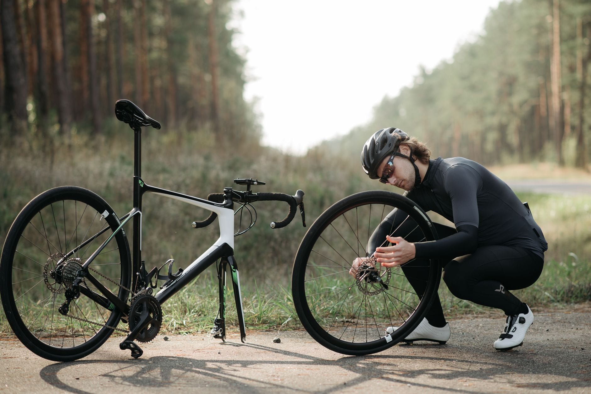 Rowerzysta naprawiający koło roweru na leśnej ścieżce